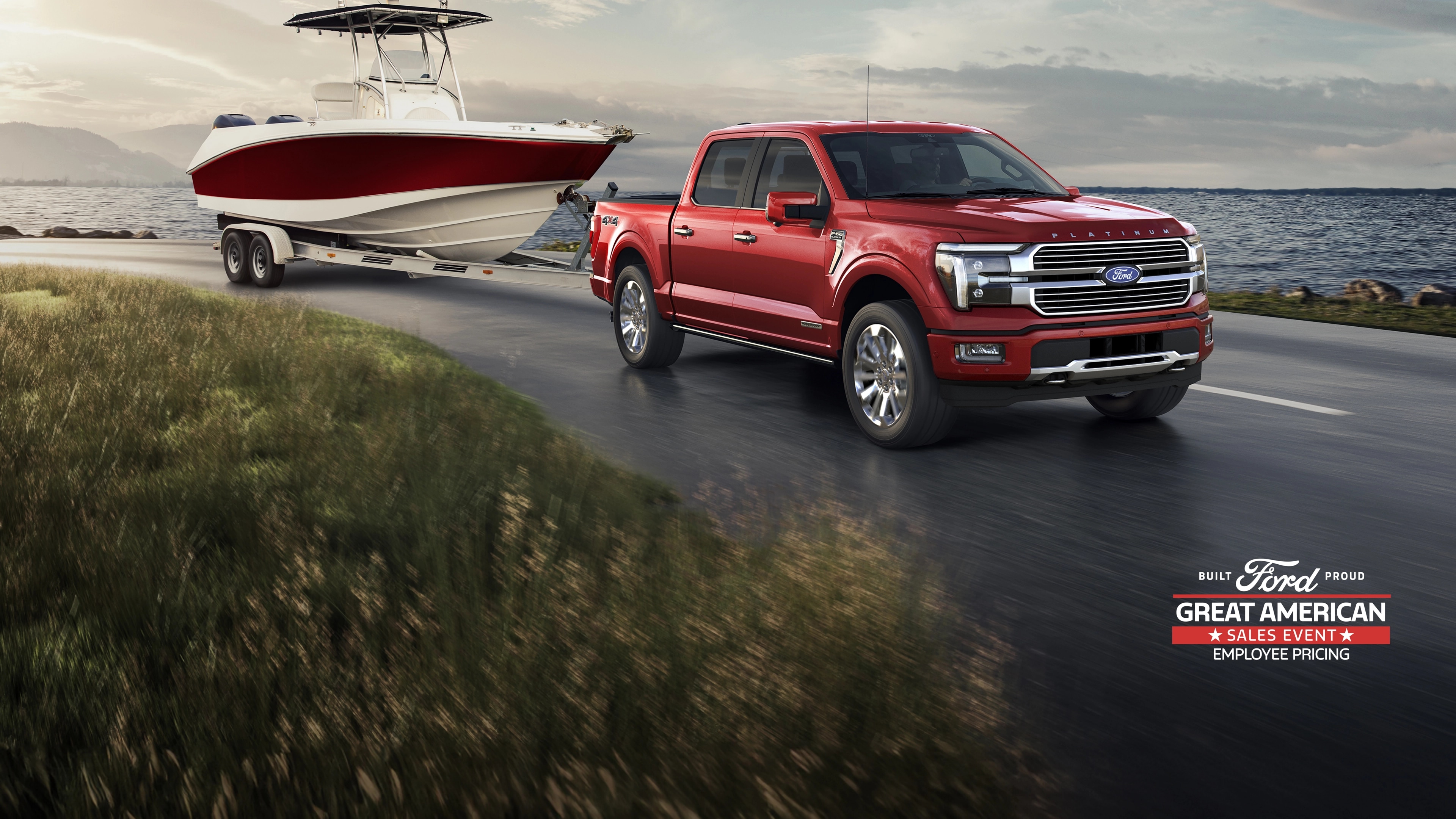 A Ford F-150® Platinum Plus truck towing a boat on a road next to a body of water