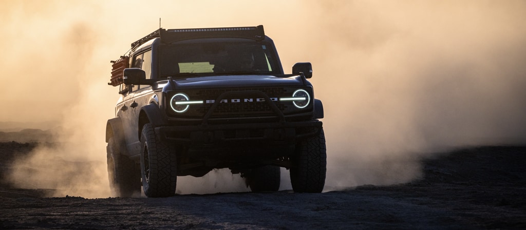2024 Ford Bronco® WildTrak® driving through dust at sunset