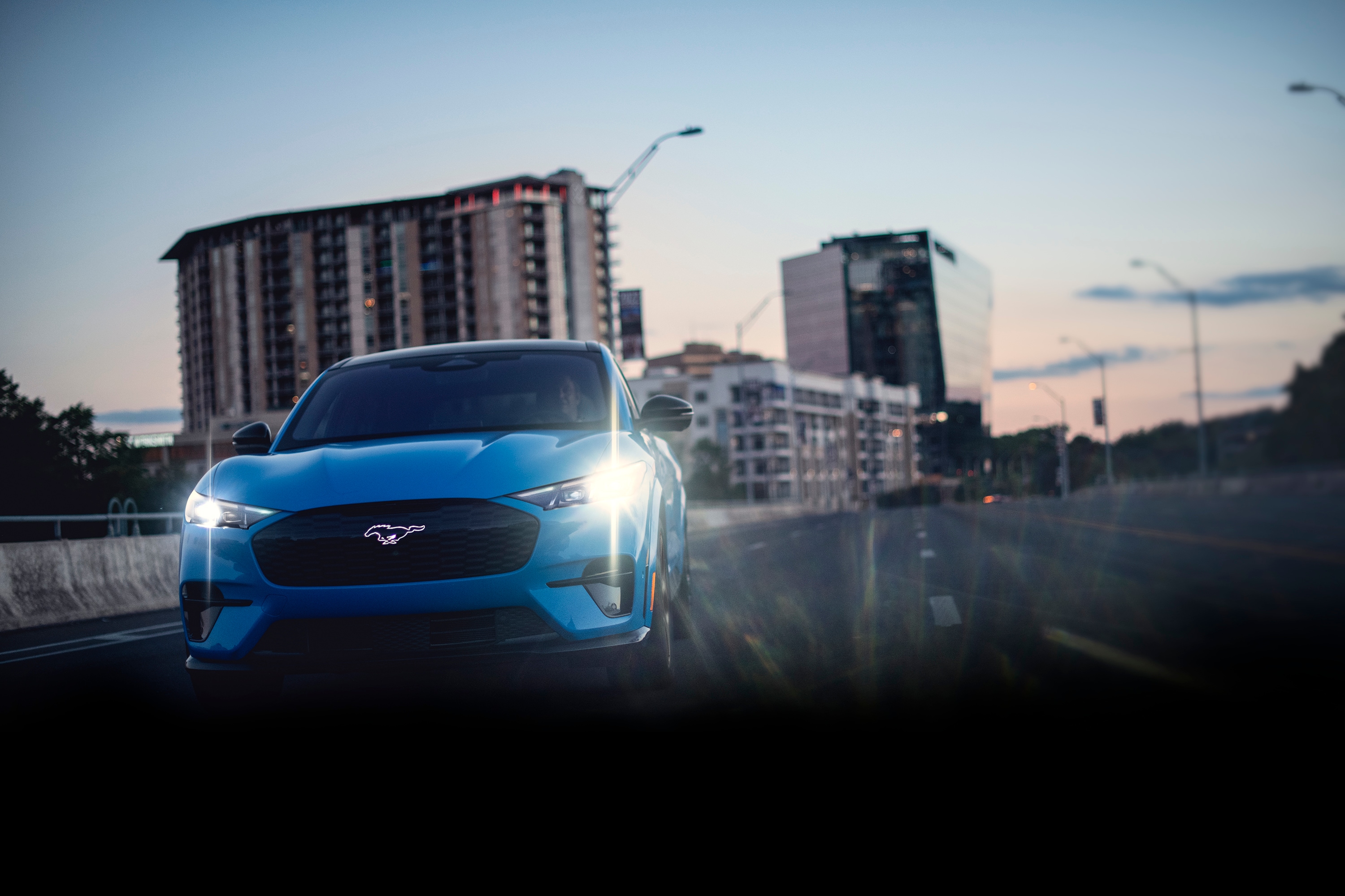 Front view of a 2026 Ford Mustang Mach-E® GT model being driven on a city freeway