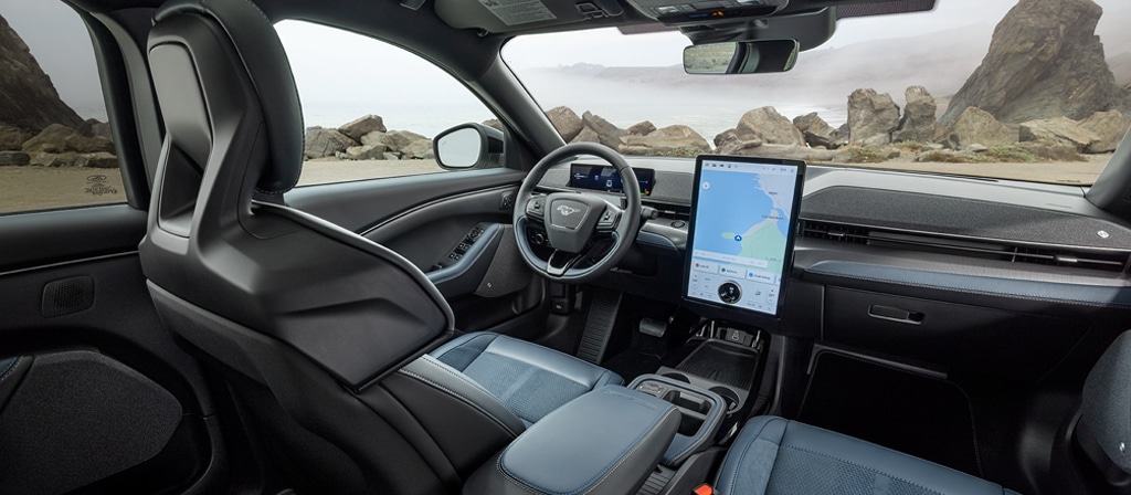 Interior of a 2026 Ford Mustang Mach-E® SUV with a view of the driver's seat, dashboard, and scenic rocky landscape
