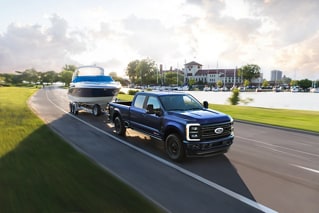 2026 Ford Super Duty® F-350® Platinum® model in Argon Blue towing a speed boat on a paved road