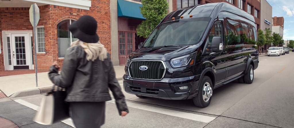 A 2026 Ford Transit® van stopped at a stop sign waiting for pedestrian to cross