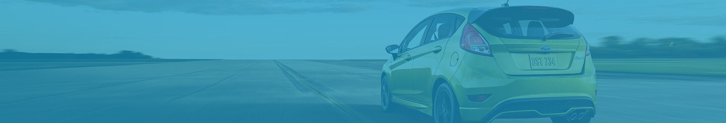 Rear shot of a Ford Fiesta shown in Outrageous Green Metallic driving down the road