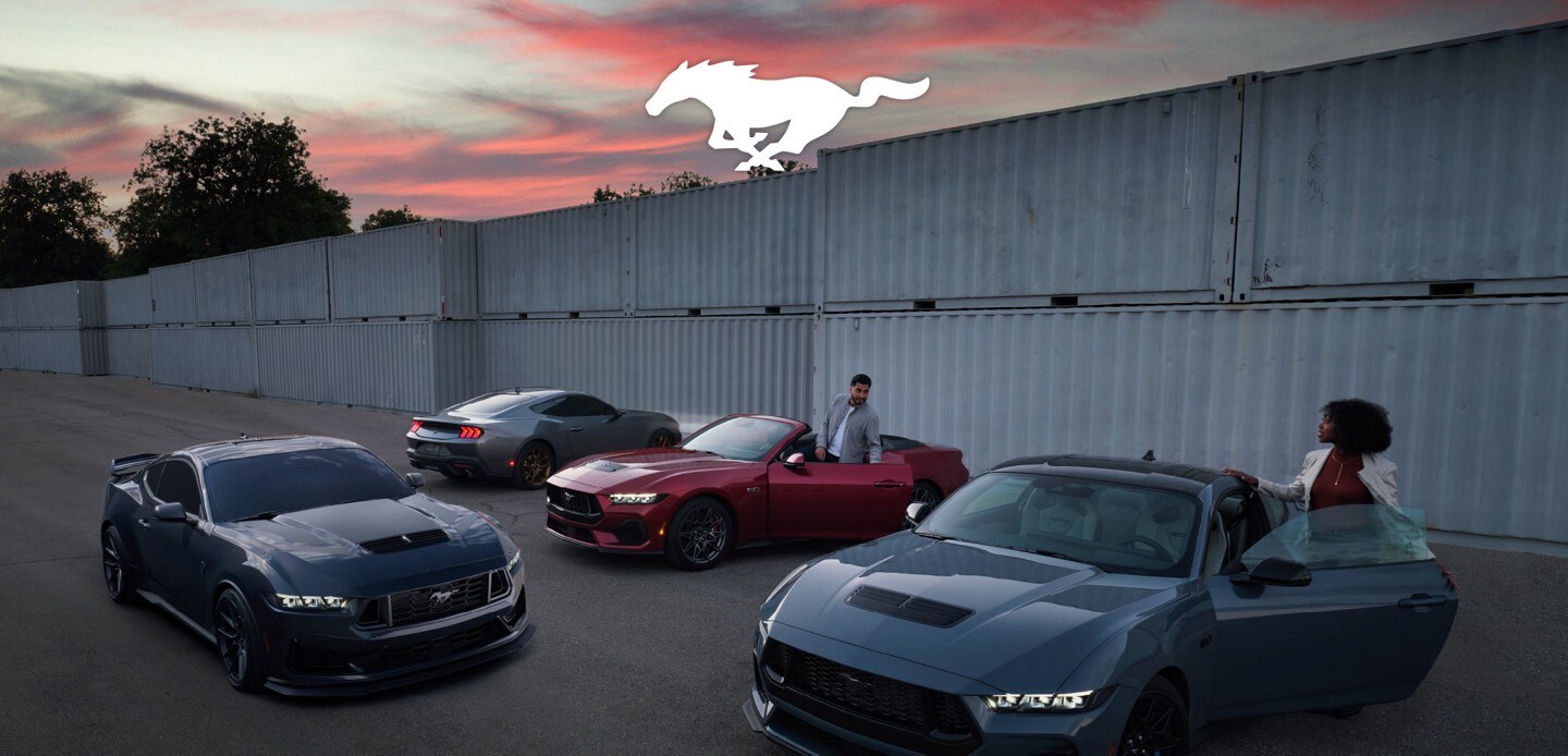 People entering a group of four 2024 Ford Mustang® models parked near shipping containers