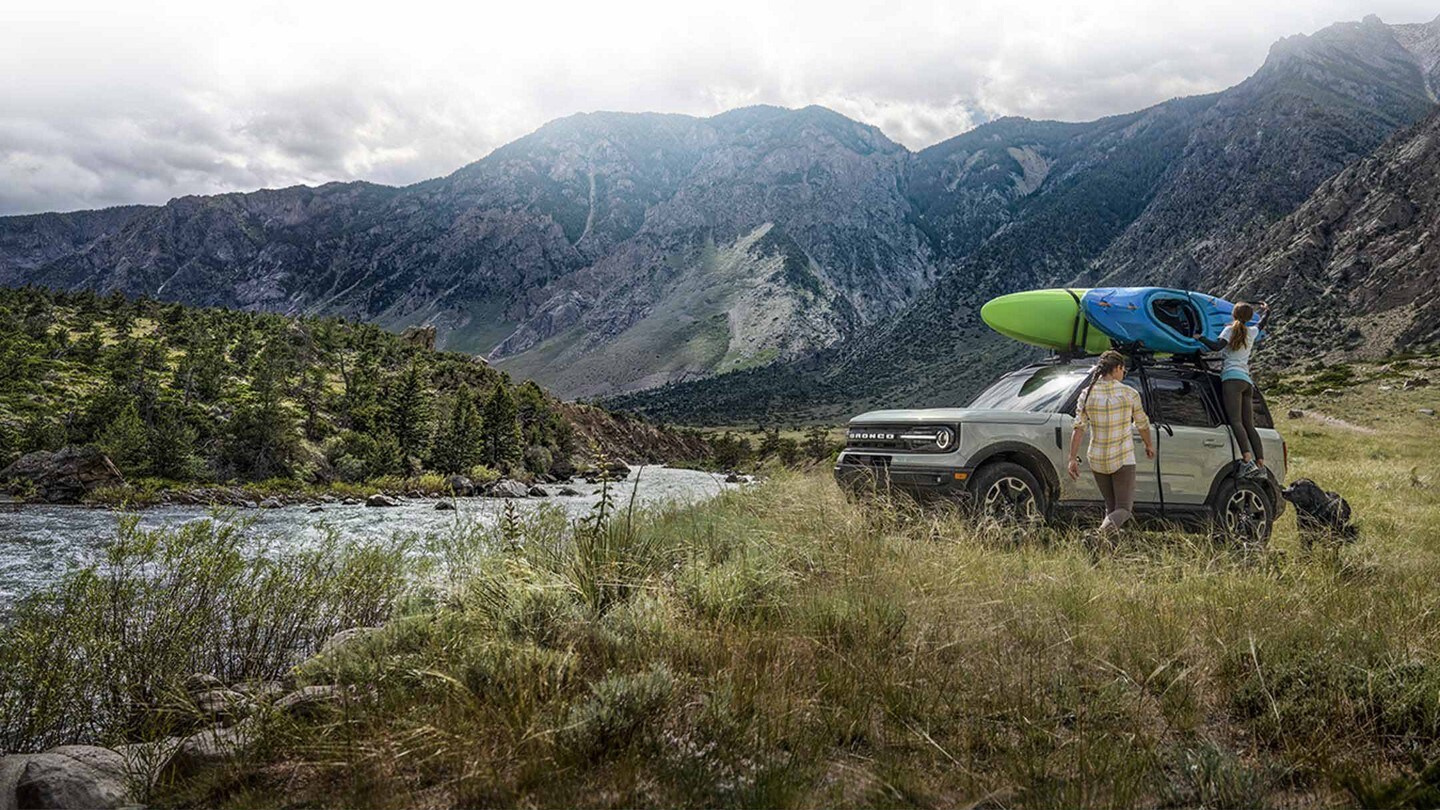 People tying a kayak on top of a 2023 Bronco Sport Outer Banks™