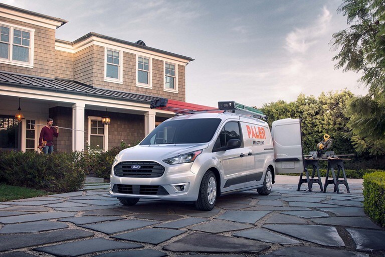 Ford fleet vehicle parked on a stone driveway in front of a brick house