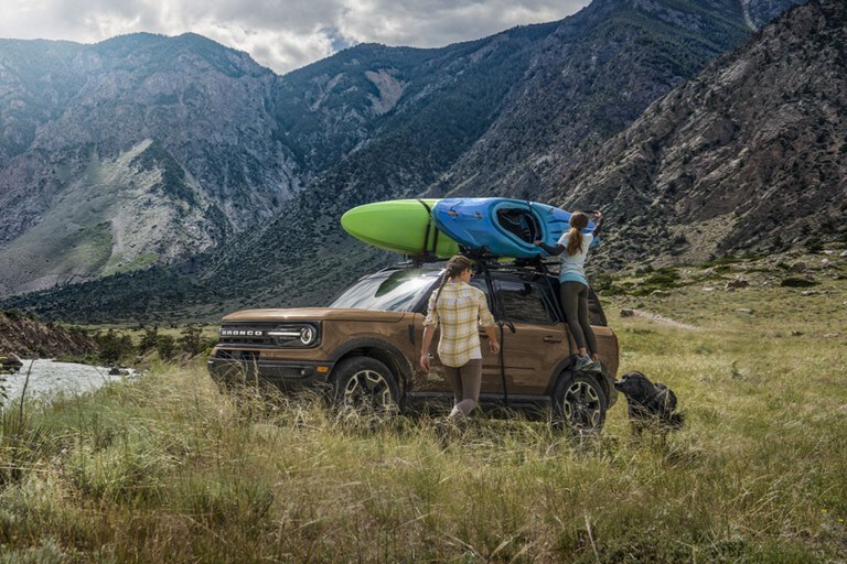 Two men remove a kayak from the top of a ford bronco sport