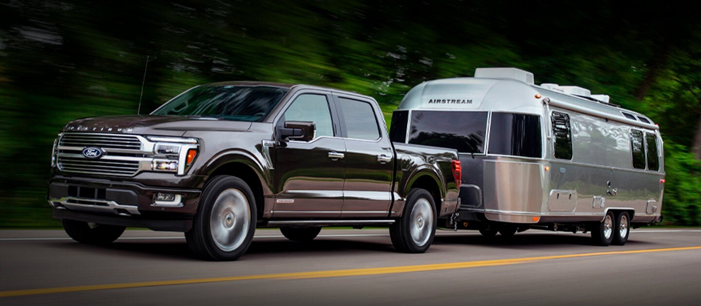 A 2024 Ford F-150® pickup in Agate Black pulling an Airstream Camper