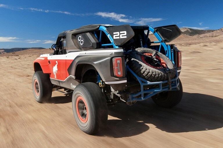 Rear view of bronco d r under being driven along a desert floor