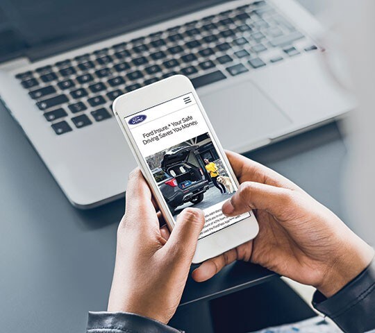 Person holding a smartphone open to the Ford Insure page
