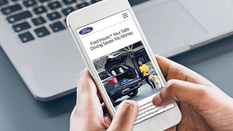 Person holding a smartphone open to the Ford Insure page