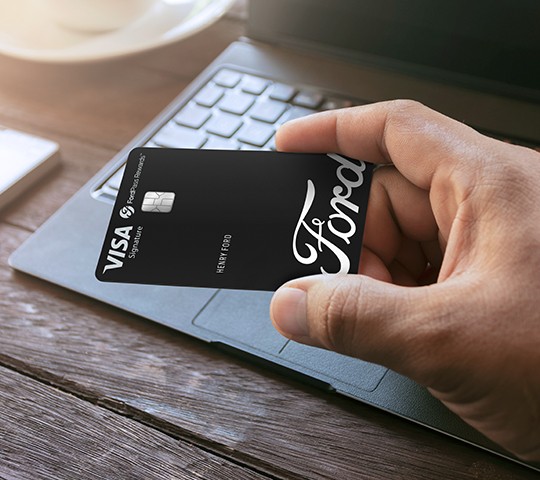 Hand is holding the black Visa card