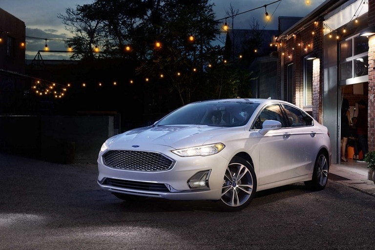 Three quarters shot of a 2020 Ford Fusion parked in a driveway with party lights hung above it