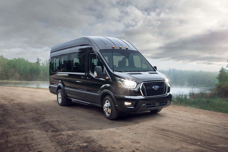 A 2021 Ford Transit Black Bus on a dirt road