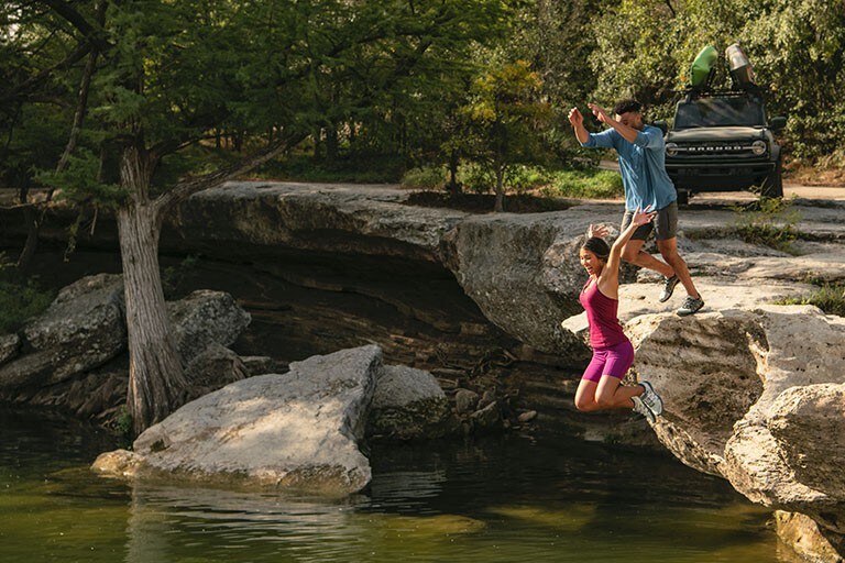 Two people are jumping off of a cliff.