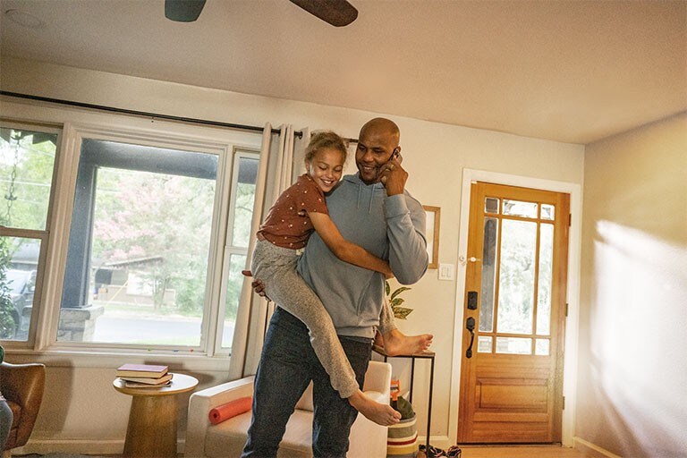 A man on a phone is holding a child.