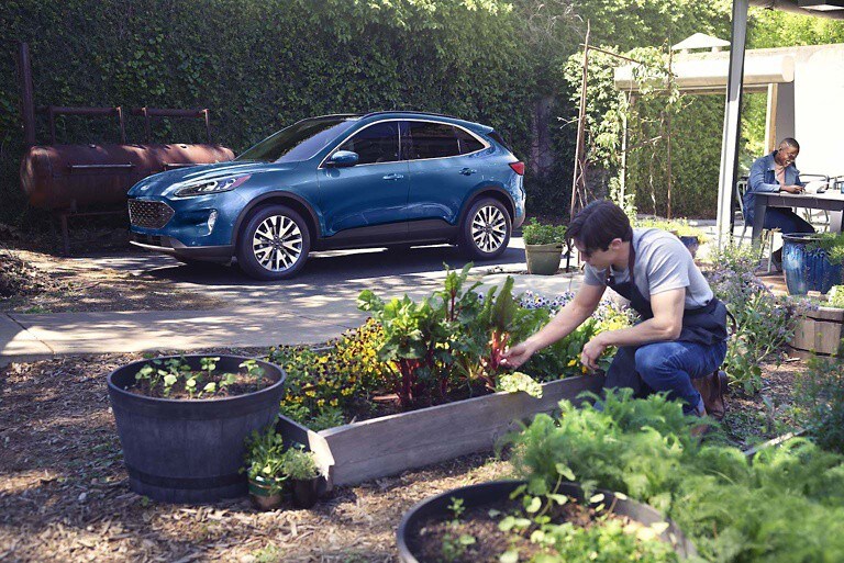 Foto de un hombre realizando tareas de jardinería y de un vehículo Ford estacionado en segundo plano