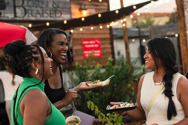 Three women laughing outside of a restaurant