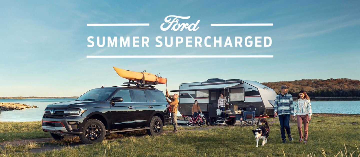 A group of people at a lakeside campsite featuring a 2023 Ford Explorer