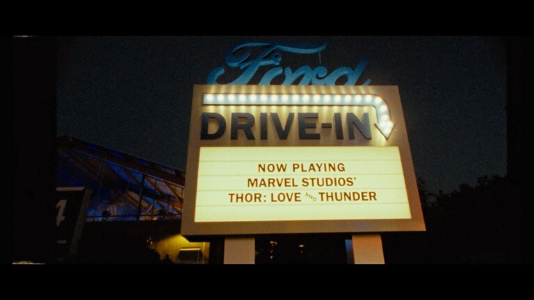 Imagen de un cartel de Drive-In grande iluminado a la noche con el logotipo de Ford en la parte superior