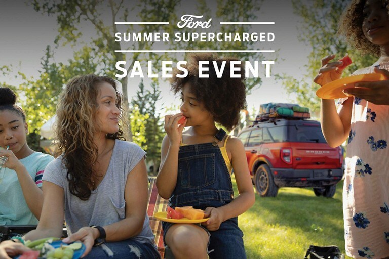 Ford Summer Supercharged Sales Event over an image of a family picnic and a 2022 Bronco Sport in background