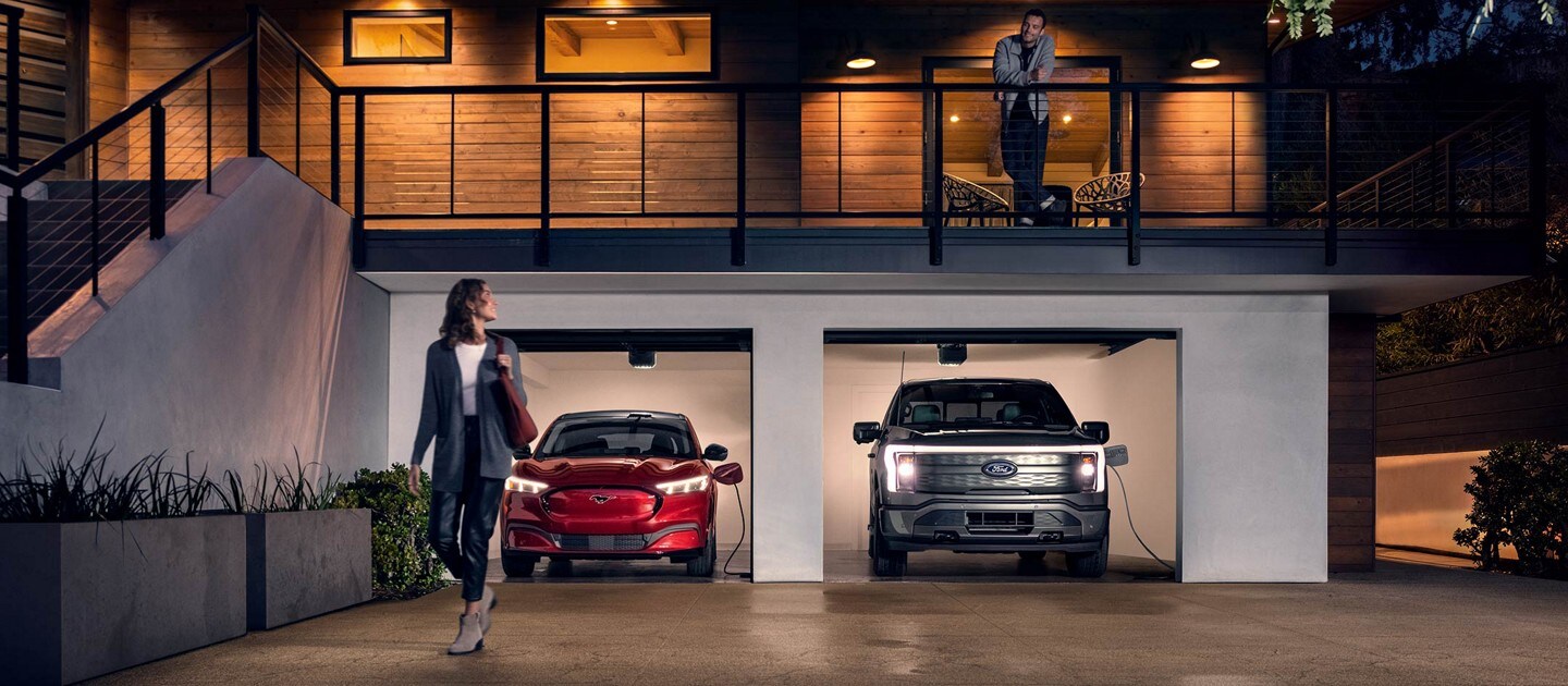 A woman walks away from an F-150® Lightning® truck and Mustang® Mach-E® charging in her garage