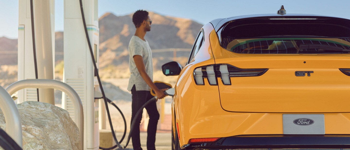 Man charging a 2022 Ford Mustang Mach-E at a public charging station