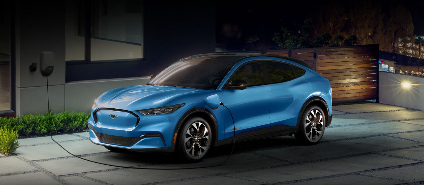 2022 Ford Mustang Mach-E plugged into a home charging station outside an upscale home