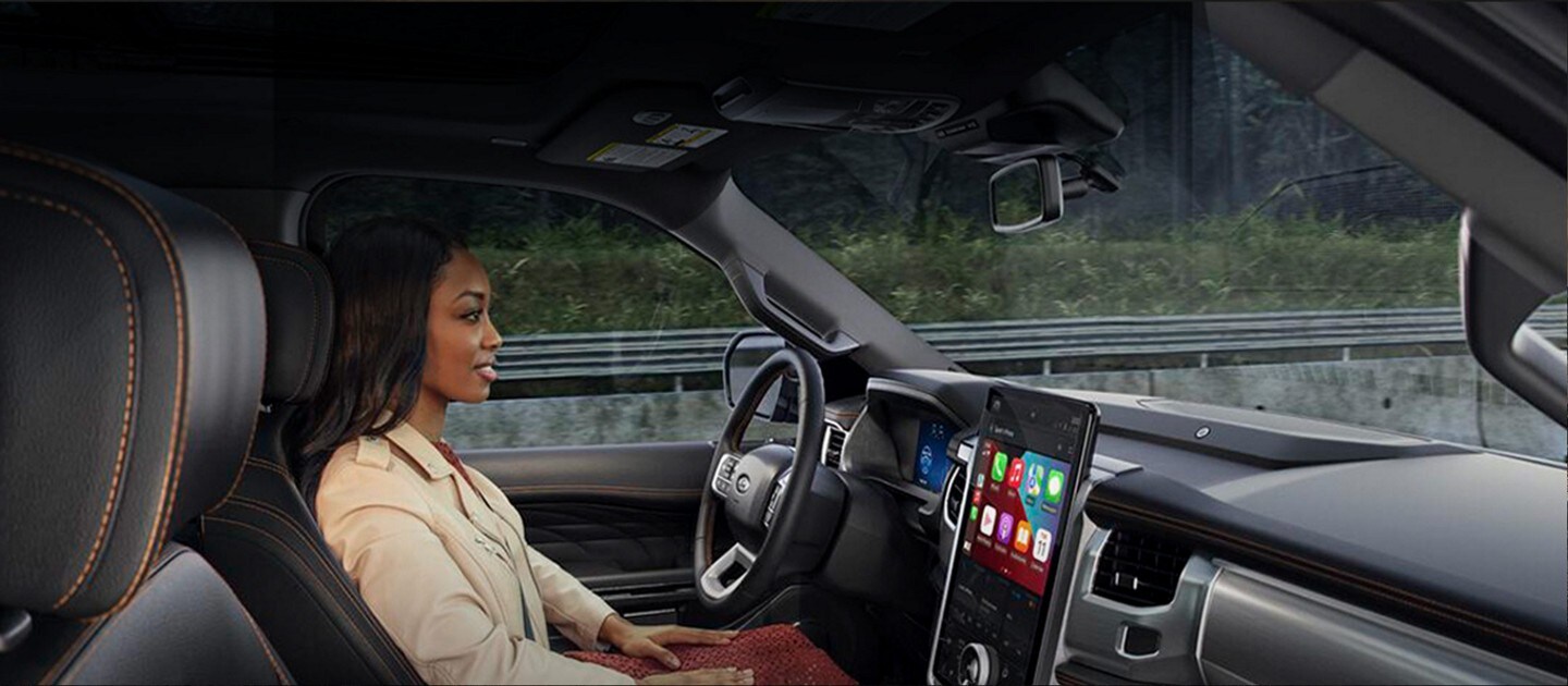 Mujer en el asiento del conductor de una camioneta Ford F-150® Lightning® usando la característica de manejo con manos libres Ford BlueCruise