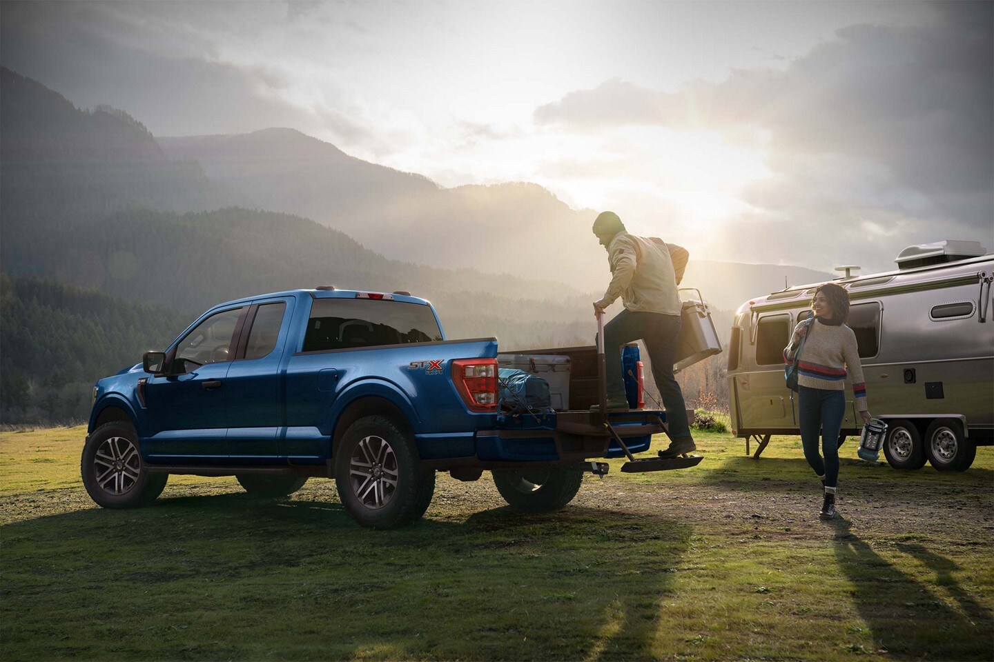Ford F-150® truck parked on grass with a man climbing on to the tailgate