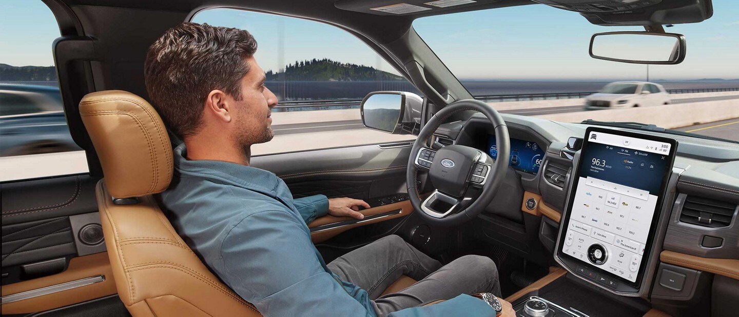 Hombre sentado al volante de su ​​​​​​​Expedition 2023 conduciendo con las manos libres en una autopista