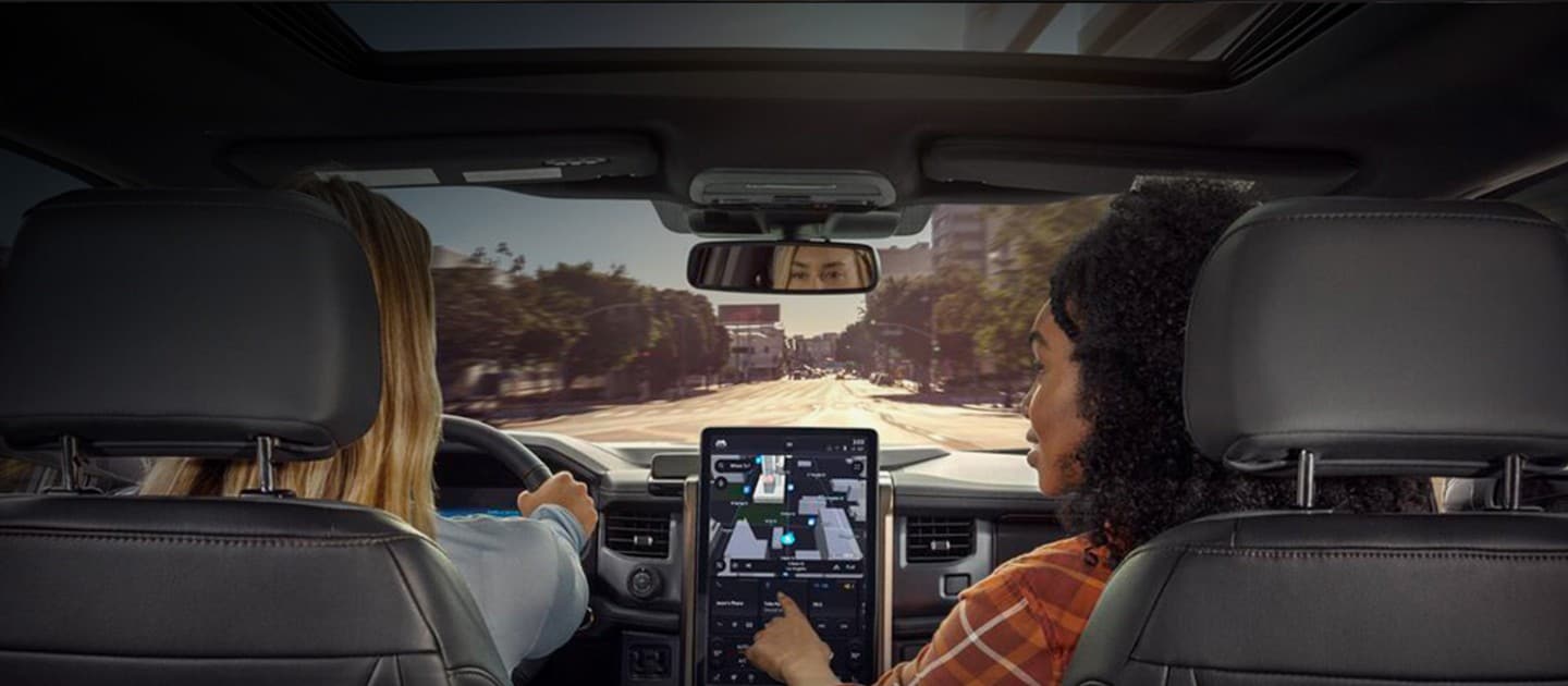 Perspectiva trasera de dos mujeres en un vehículo Ford usando las opciones de Navegación Conectada
