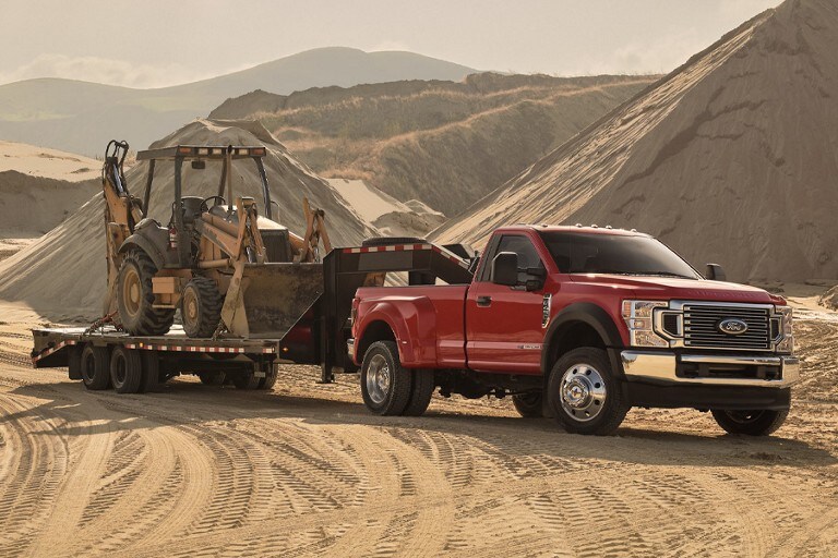 Una Ford F-250 Super Duty 2022 remolcando un tractor grande en un sitio de construcción