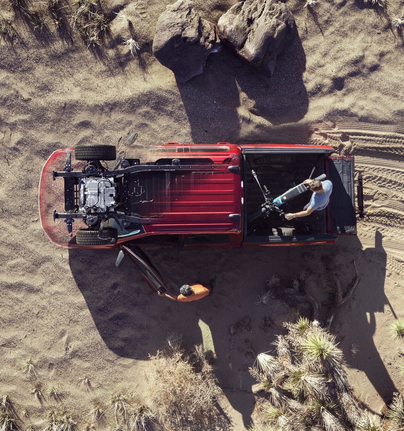 Extreme overhead shot of a man unloading his bike from the back of his Rapid-Red 2022 F-150 Lightning.