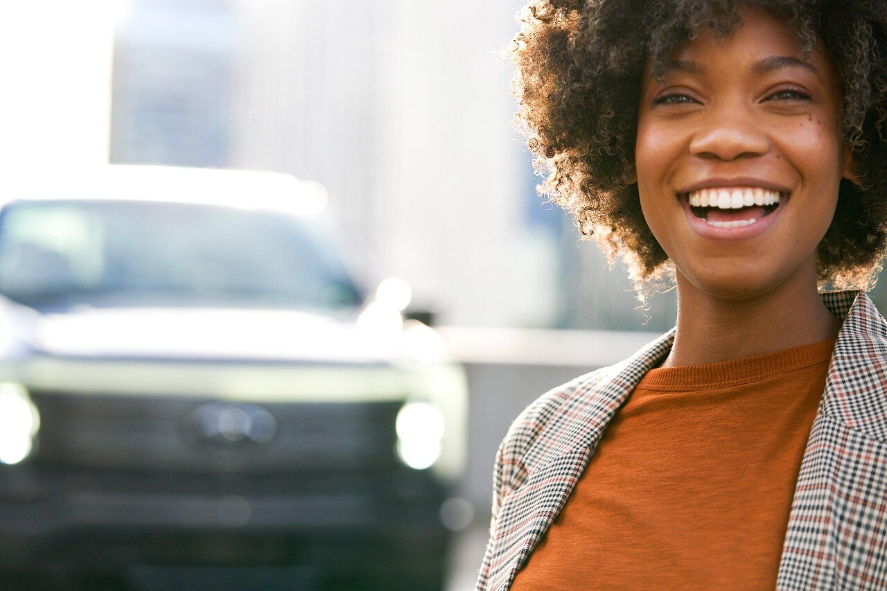 A woman smiling with a 2022 Ford® F-150 Lightning in the background