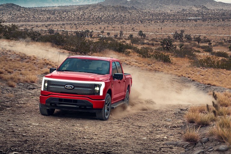 Rapid-Red 2022 F-150 Lightning driving down a desert dirt road.