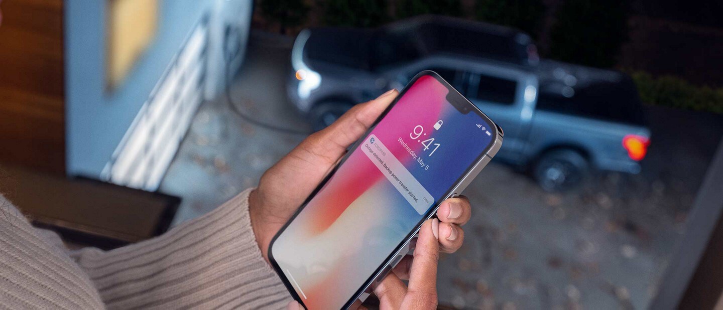Una mujer recibe una alerta por mensaje de la Potencia de Respaldo Inteligente Ford en su smartphone