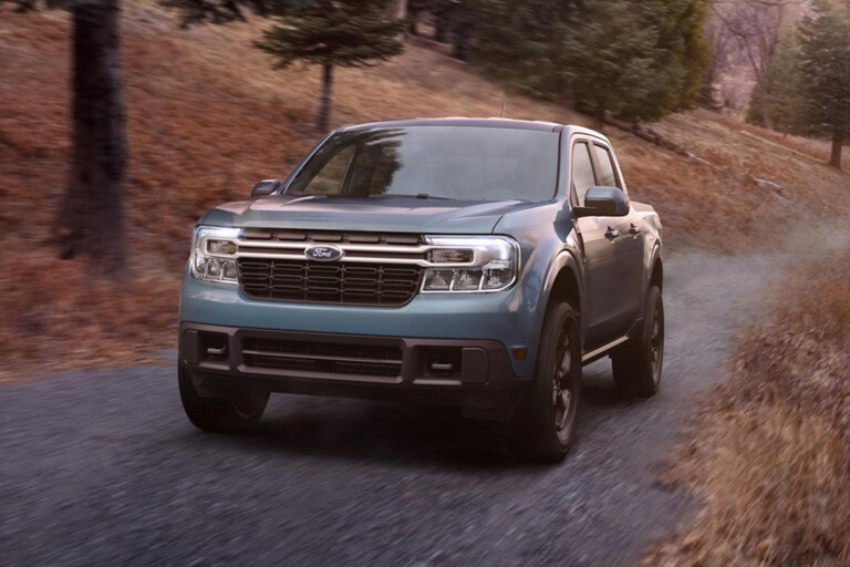 2022 Ford® Maverick LARIAT with available FX4 package drives down a dirt road at dusk