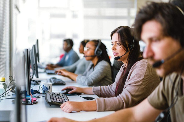 Un trabajador de atención al cliente frente a una computadora con un auricular puesto