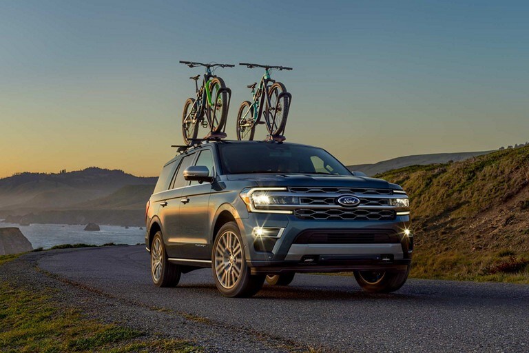2022 Ford Expedition Platinum in Infinite Blue being driven on a road with an available rooftop bike rack