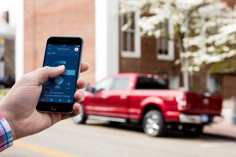 A hand using the FordPass app to interact with the 2020 Ford F one fifty in the background
