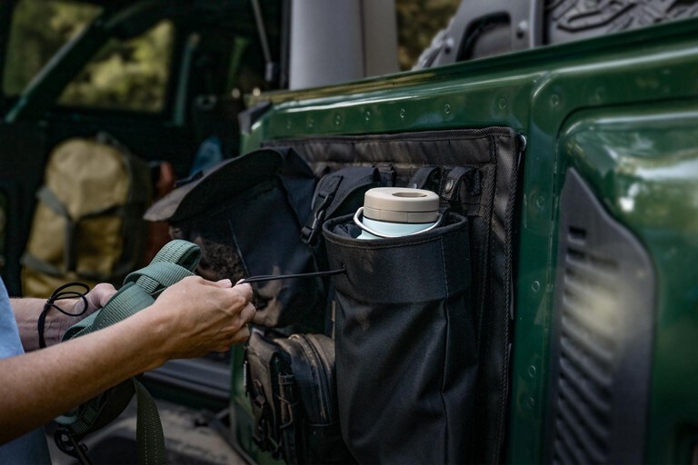 Interior of a 2023 Ford Bronco® SUV with a person strapping in supplies on tailgate