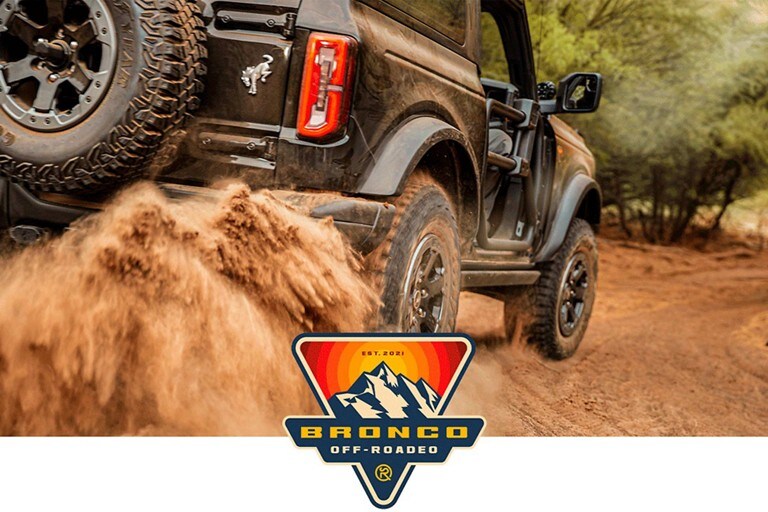 Logo Ford Bronco® Off-Roadeo con un modelo Ford Bronco® 2023 andando por un sendero agreste