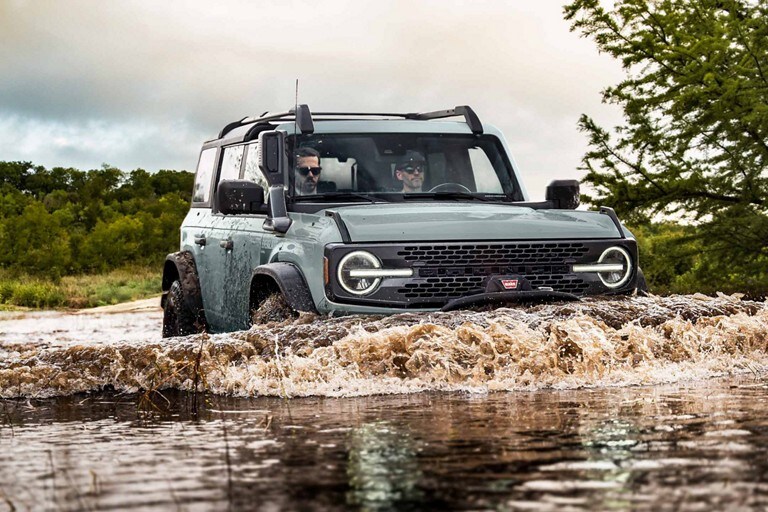 A 2023 Ford Bronco® Everglades™ in Cactus Gray being driven through water