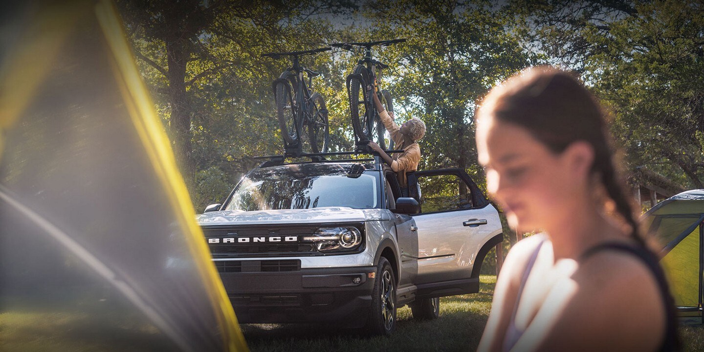 Una Ford Bronco® Sport 2023 de fondo con una mujer parada cerca del vehículo