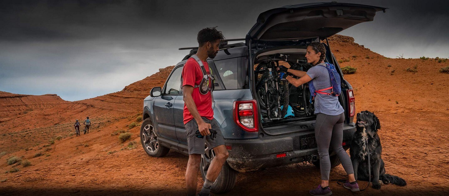 Two people standing near the back of the vehicle