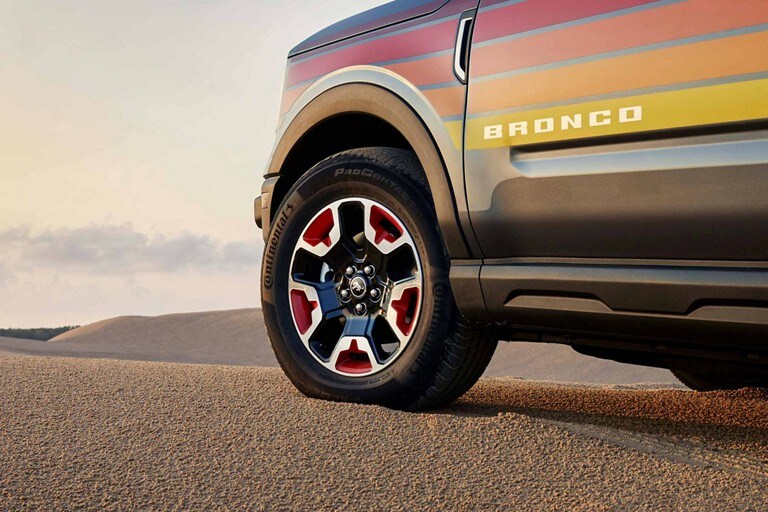 Se muestra una SUV Ford Bronco® Sport Free Wheeling™ 2024 con ruedas de aluminio pintado en Ebony y Race Red de 17 pulgadas estacionada en el desierto