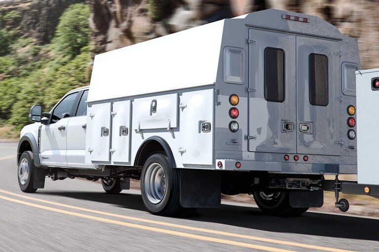 2023 Ford Super Duty® Chassis Cab with utility box upfit and trailer in tow being driven on the highway