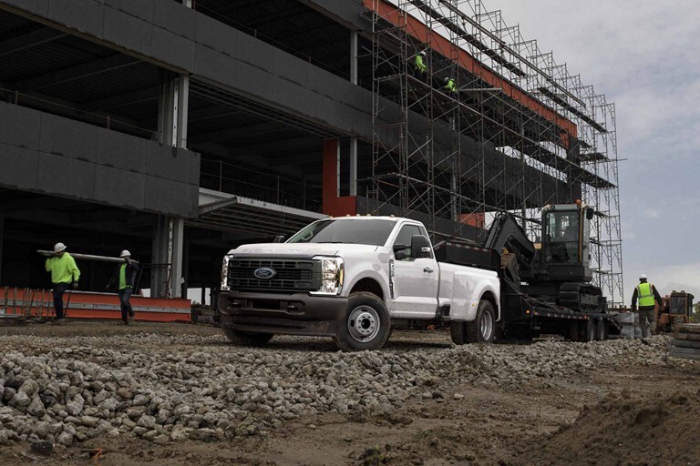2024 Ford Chassis Cab truck parked at a building construction site with equipment behind it