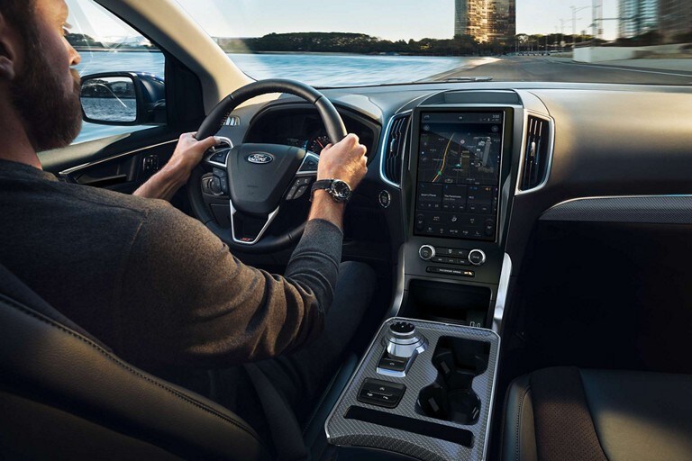 Primer plano de un hombre conduciendo una Ford Edge® 2023 con las manos en el volante térmico